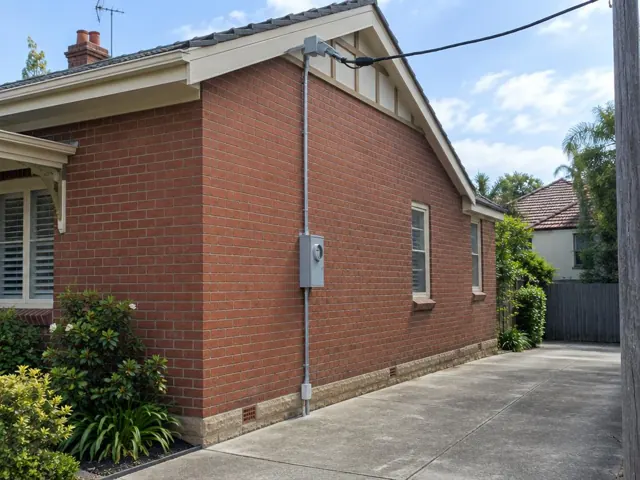 Brick house exterior with overhead service cable and point-of-attachment bracket on the gable wall in Rose Bay